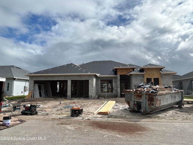 rear view of property with concrete block siding and roof with shingles