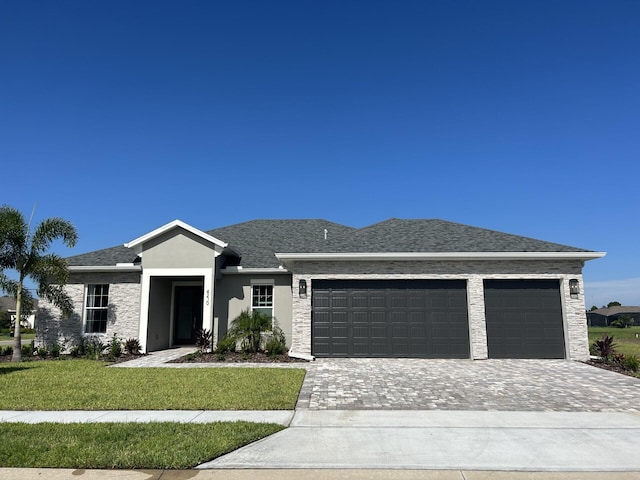 view of front of home featuring a garage, roof with shingles, decorative driveway, stucco siding, and a front yard