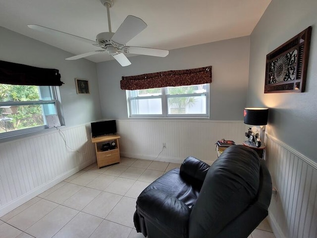 living area with light tile floors and ceiling fan