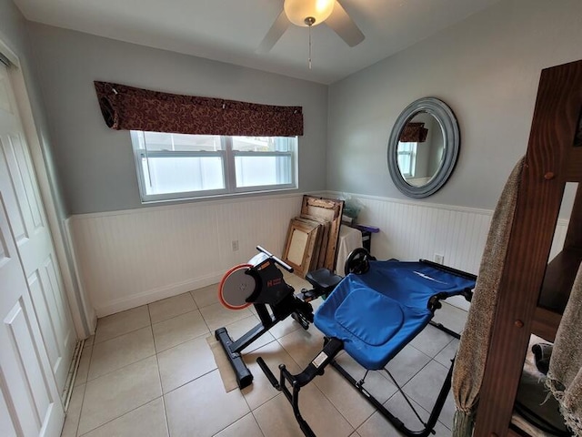 exercise room with ceiling fan and light tile floors