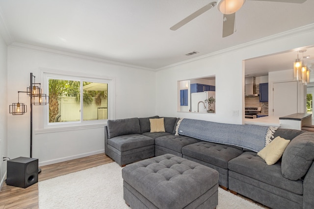 living room featuring crown molding, light hardwood / wood-style floors, and ceiling fan