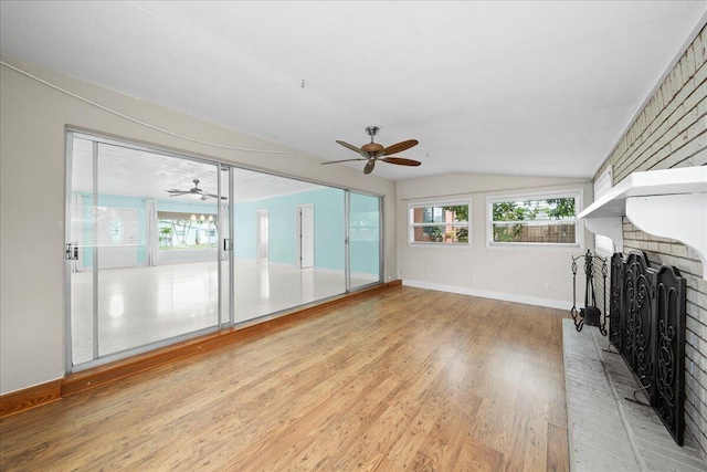 unfurnished living room with vaulted ceiling, ceiling fan, light wood-type flooring, and a fireplace