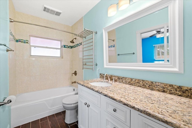 full bathroom with vanity, toilet, a healthy amount of sunlight, and tiled shower / bath