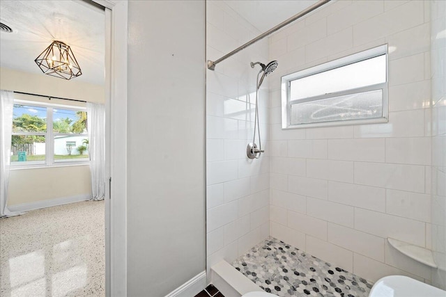 bathroom with a tile shower and toilet