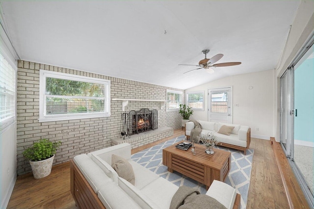 living room featuring brick wall, ceiling fan, lofted ceiling, a fireplace, and hardwood / wood-style flooring