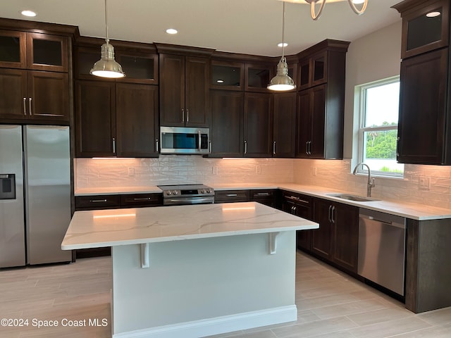 kitchen featuring sink, a kitchen bar, decorative backsplash, a kitchen island, and appliances with stainless steel finishes