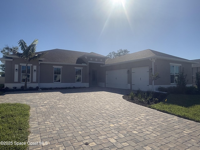 single story home featuring decorative driveway, an attached garage, and stucco siding