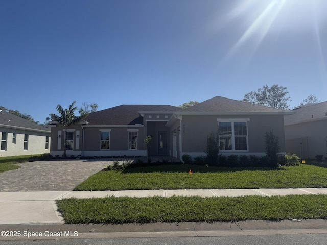 view of front facade featuring a front yard, decorative driveway, and stucco siding