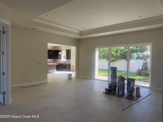 interior space featuring crown molding, a tray ceiling, visible vents, and baseboards