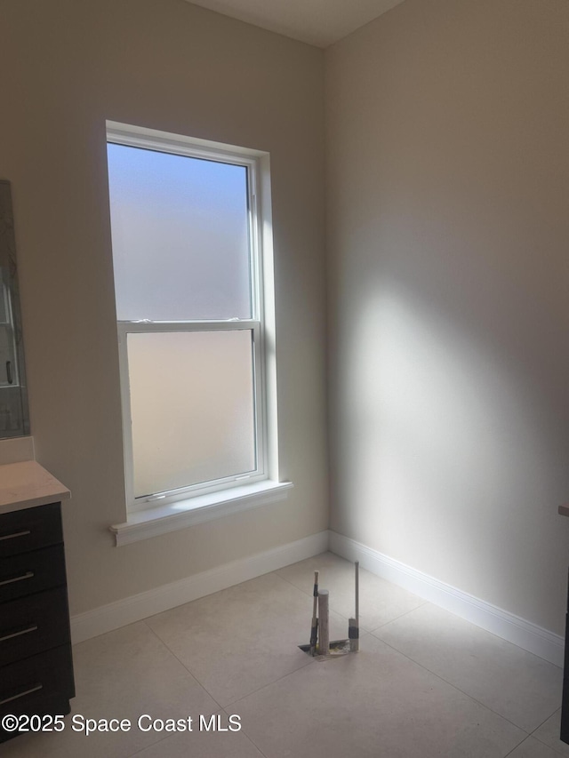 unfurnished room with light tile patterned floors and baseboards