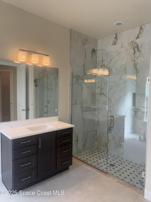 full bathroom featuring a marble finish shower and vanity