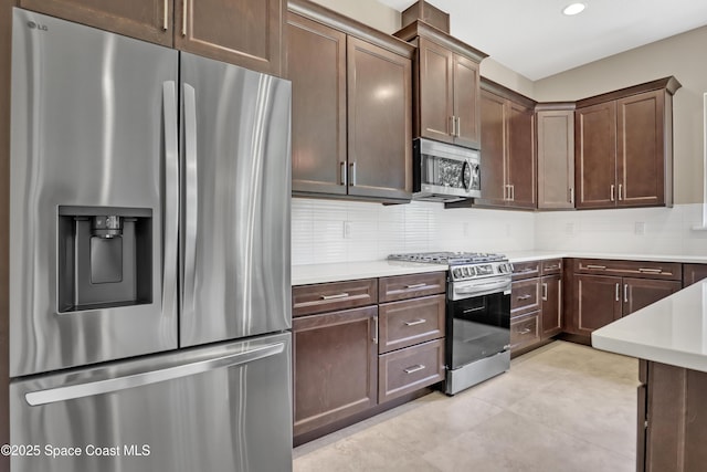 4335 Negal Cir, Melbourne, FL 32901 - kitchen featuring appliances with stainless steel finishes, light countertops, tasteful backsplash, dark brown cabinets, and light tile patterned floors