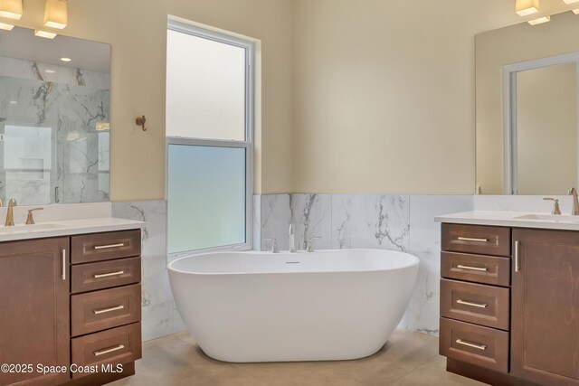 4335 Negal Cir, Melbourne, FL 32901 - full bathroom with two vanities, tile walls, a marble finish shower, a freestanding tub, and a wainscoted wall