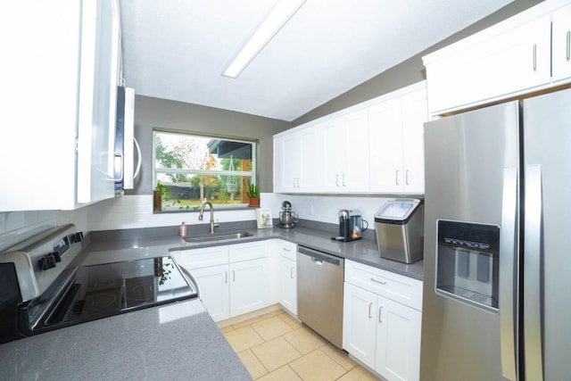 kitchen featuring tasteful backsplash, vaulted ceiling, white cabinets, and appliances with stainless steel finishes