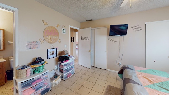 bedroom featuring a textured ceiling, light tile flooring, and ceiling fan