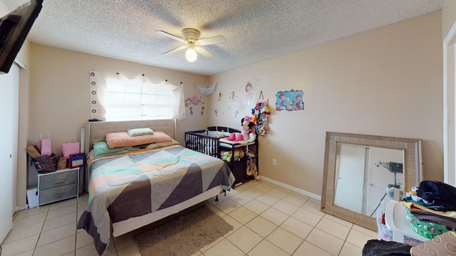 tiled bedroom with ceiling fan and a textured ceiling