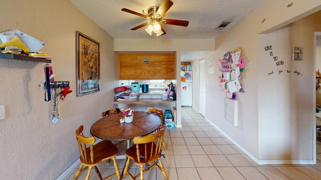 dining room with light tile flooring, ceiling fan, and a textured ceiling