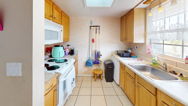 kitchen featuring white appliances, sink, light tile floors, a skylight, and decorative light fixtures