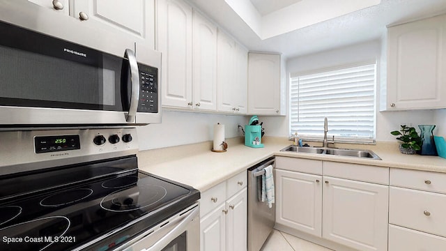 kitchen featuring white cabinetry, sink, light tile flooring, and stainless steel appliances