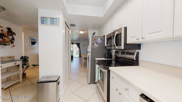 kitchen with stainless steel appliances, white cabinets, and light tile floors