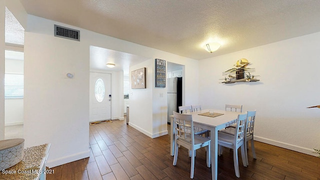 dining space with a textured ceiling and dark hardwood / wood-style floors