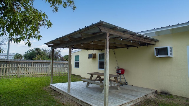 wooden deck with a wall unit AC and a yard