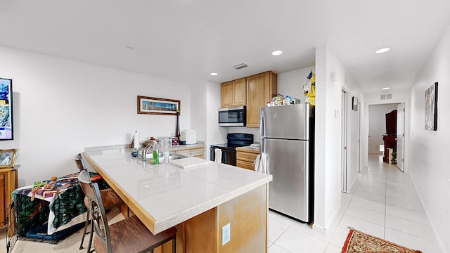 kitchen with light tile flooring, kitchen peninsula, stainless steel appliances, a kitchen breakfast bar, and sink