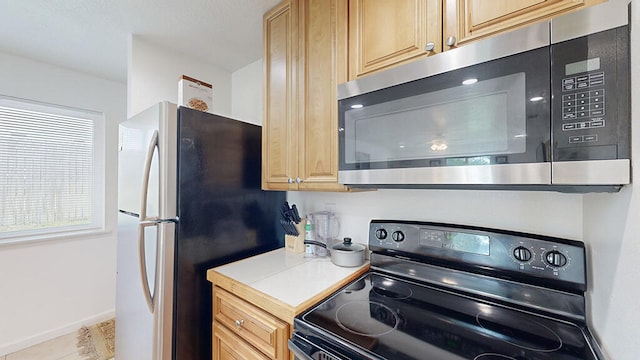 kitchen featuring tile floors, stainless steel appliances, and light brown cabinets