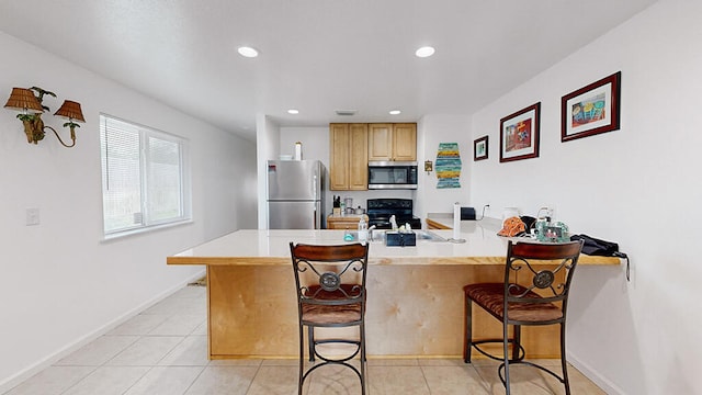 kitchen with a breakfast bar, light tile floors, kitchen peninsula, and appliances with stainless steel finishes