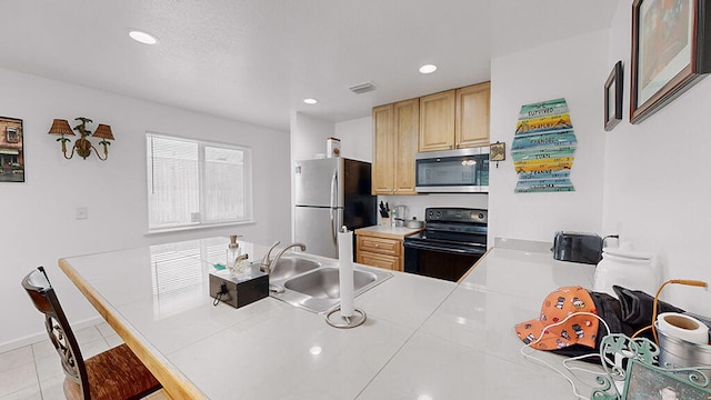 kitchen featuring light brown cabinets, kitchen peninsula, light tile flooring, sink, and appliances with stainless steel finishes