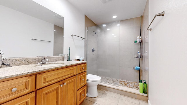 bathroom with tile floors, tiled shower, toilet, and vanity