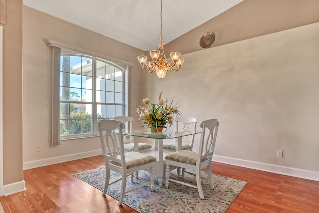 dining room featuring lofted ceiling, light hardwood / wood-style floors, and a notable chandelier