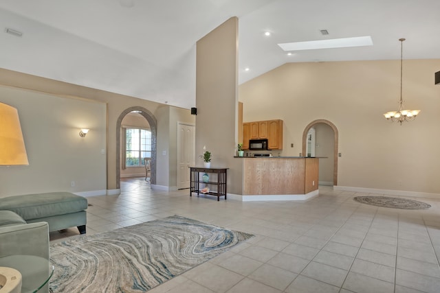 tiled living room with a skylight, a chandelier, and high vaulted ceiling