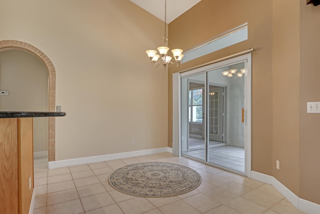 entryway featuring light tile floors, a notable chandelier, and a towering ceiling