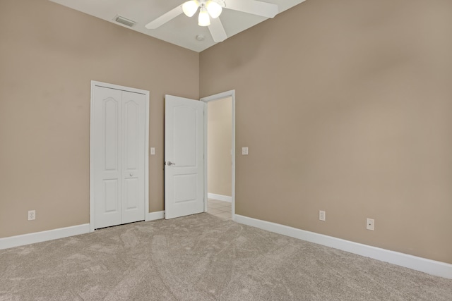 unfurnished bedroom with light carpet, a closet, ceiling fan, and a towering ceiling