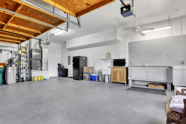 garage featuring heating utilities, ceiling fan, black fridge, and a garage door opener