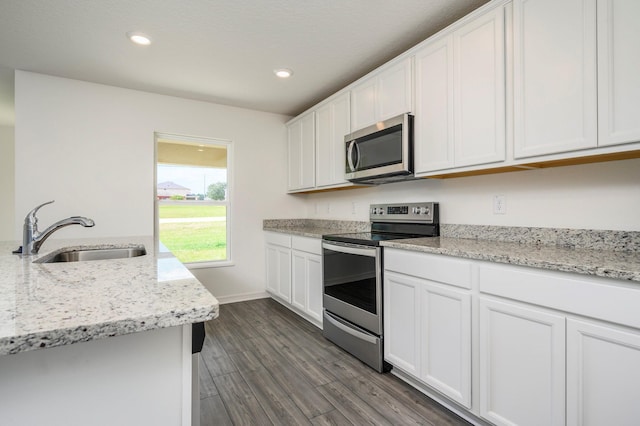 kitchen featuring light stone countertops, dark wood-type flooring, sink, stainless steel appliances, and white cabinets