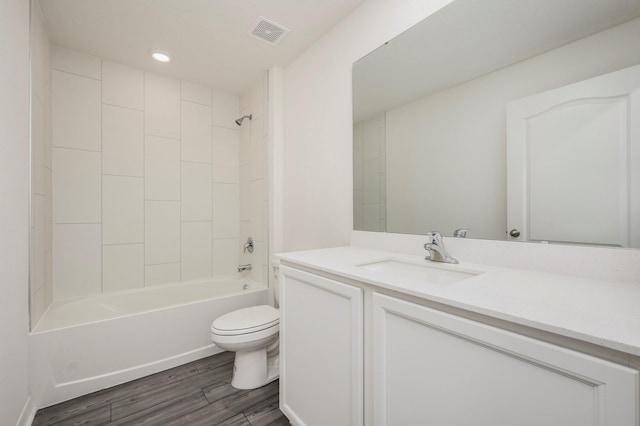 full bathroom with tiled shower / bath, toilet, large vanity, and hardwood / wood-style flooring