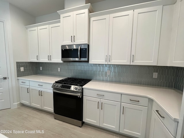 kitchen featuring stainless steel appliances, white cabinets, light hardwood / wood-style flooring, and decorative backsplash