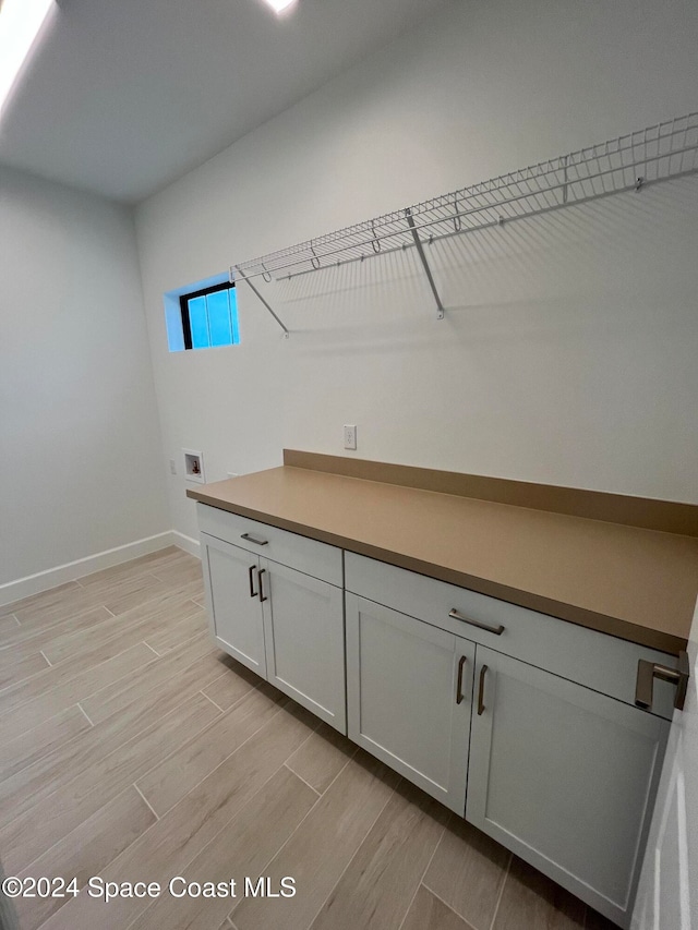 laundry area with light hardwood / wood-style floors, hookup for a washing machine, and cabinets