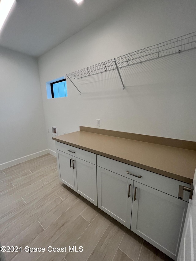 8526 Lyside Dr, Melbourne, FL 32940 - laundry area with light wood finished floors, hookup for a washing machine, cabinet space, and baseboards