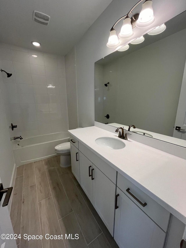 full bathroom featuring hardwood / wood-style floors, vanity, toilet, and tiled shower / bath combo