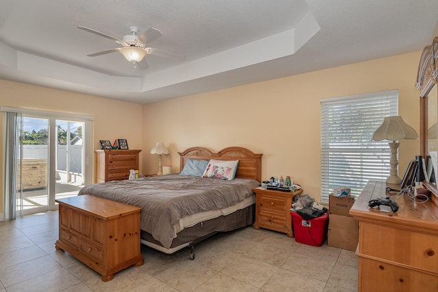 bedroom featuring access to exterior, ceiling fan, a raised ceiling, and light tile floors