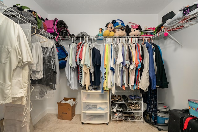 walk in closet with light tile floors