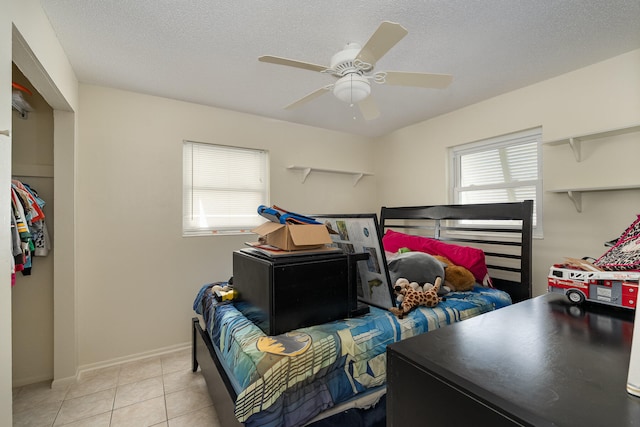 tiled bedroom with ceiling fan and a textured ceiling