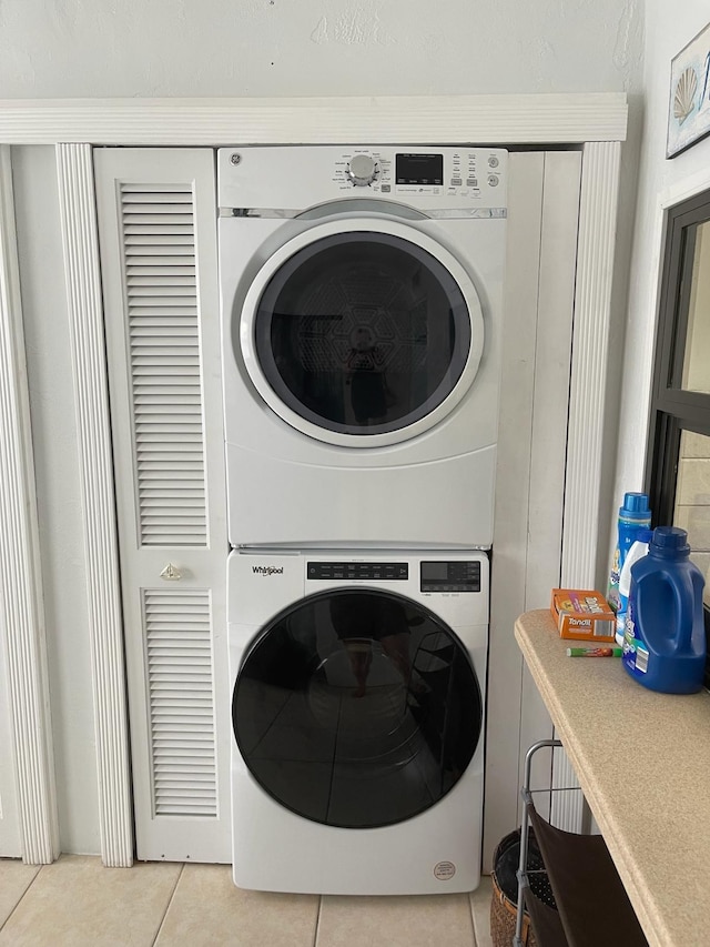 washroom featuring light tile floors and stacked washer / drying machine