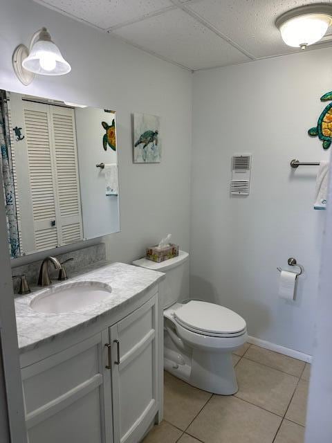 bathroom with a paneled ceiling, oversized vanity, toilet, and tile floors