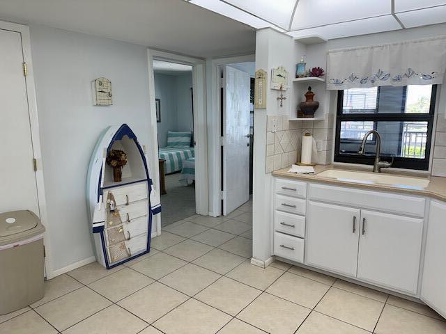 kitchen featuring sink, white cabinets, tasteful backsplash, and light tile floors