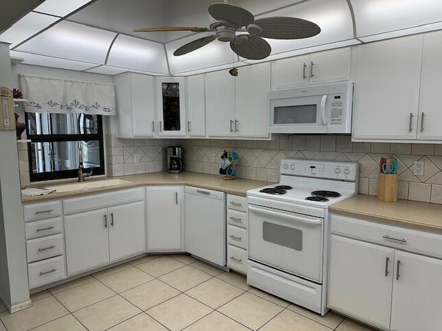 kitchen featuring backsplash, ceiling fan, white cabinetry, and white appliances