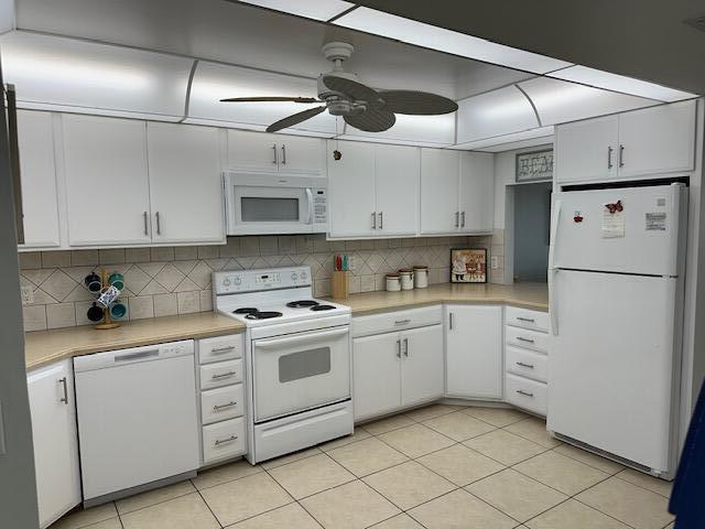 kitchen featuring white appliances, backsplash, white cabinetry, and ceiling fan